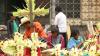 A man and several children construct crosses made of flowers and broad folded leaves