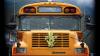 A yellow school bus is adorned at its front with a cross made of flowers and broad folded leaves