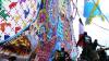 People stand near towering handmade kites, which include panels of words, patterns and pictures.